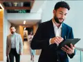 Hombre de negocios revisa su tablet, preparándose para sus dobles grados con relaciones internacionales.