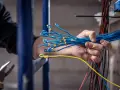 Mano sujetando un manojo de cables azules, preparándose para un trabajo de grado superior electricidad.