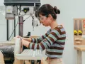 Joven en taller de ingeniería diseño industrial, concentrada en lijadora.