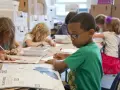 Niños concentrados en una actividad artística, guiados por un técnico superior en educación infantil.