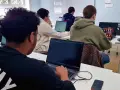 Estudiantes de **grado medio informática** concentrados frente a sus ordenadores en un aula.