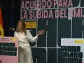 Una mujer habla en un podio con el lema "Acuerdo para la subida del SMI". Se discute cuánto cobra un trabajador social.