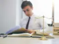 Estudiante de derecho concentrado en sus estudios, con una balanza de la justicia y libros. Averigua cuanto dura la carrera de derecho.