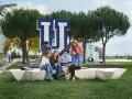 Estudiantes discuten en el campus de la Universidad Francisco de Vitoria, rodeados de árboles y el logo de la institución. Buenas **universidad francisco de vitoria opiniones** para elegir tu futuro.