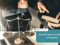 Balanza de la justicia y abogados discutiendo un caso. La imagen pregunta: ¿Cuánto gana un abogado en España?