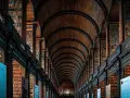 Pasillos de una biblioteca antigua con estanterías de madera repletas de libros, un ejemplo de la majestuosidad que se estudia en arquitectura.
