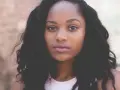 Primer plano de una mujer joven con cabello oscuro y rizado, ojos marrones y labios rosados. Imágenes de personas sin derechos de autor.