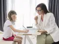 Psicóloga atenta a una niña que dibuja. La sesión es parte de la terapia infantil, y la pregunta de cuánto cobra un psicólogo en España es clave para acceder a estos servicios.