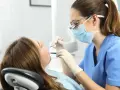 Dentista revisa la boca de una paciente. ¿Cuántos años son la carrera de odontología?