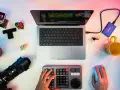 Un escritorio con un portátil mostrando un editor de video, un teclado de control, cámara, disco duro y taza. Ideal para los mejores editores de video para PC.