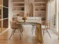 Comedor moderno con mesa de cristal y sillas de ratán. Estanterías empotradas y un toque de diseño de interiores cálido.