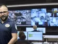 Vigilante de seguridad con certificado de discapacidad, sonriendo ante cámaras de vigilancia.