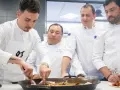 Cuatro chefs observan atentamente una paella. Se debate la diferencia entre chef y cocinero mientras preparan el plato.