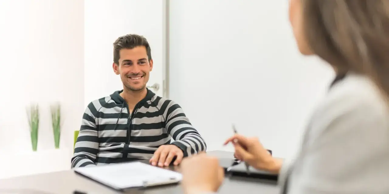Hombre sonriente en entrevista para una **formación en centros de trabajo**.