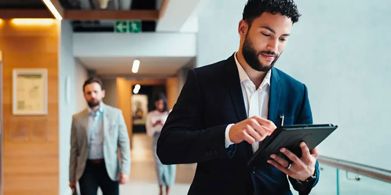Hombre de negocios revisa su tablet, preparándose para sus dobles grados con relaciones internacionales.