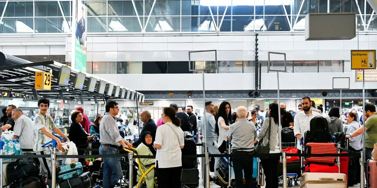 Gente haciendo fila para trabajar en el aeropuerto, con equipaje y mostradores de facturación.