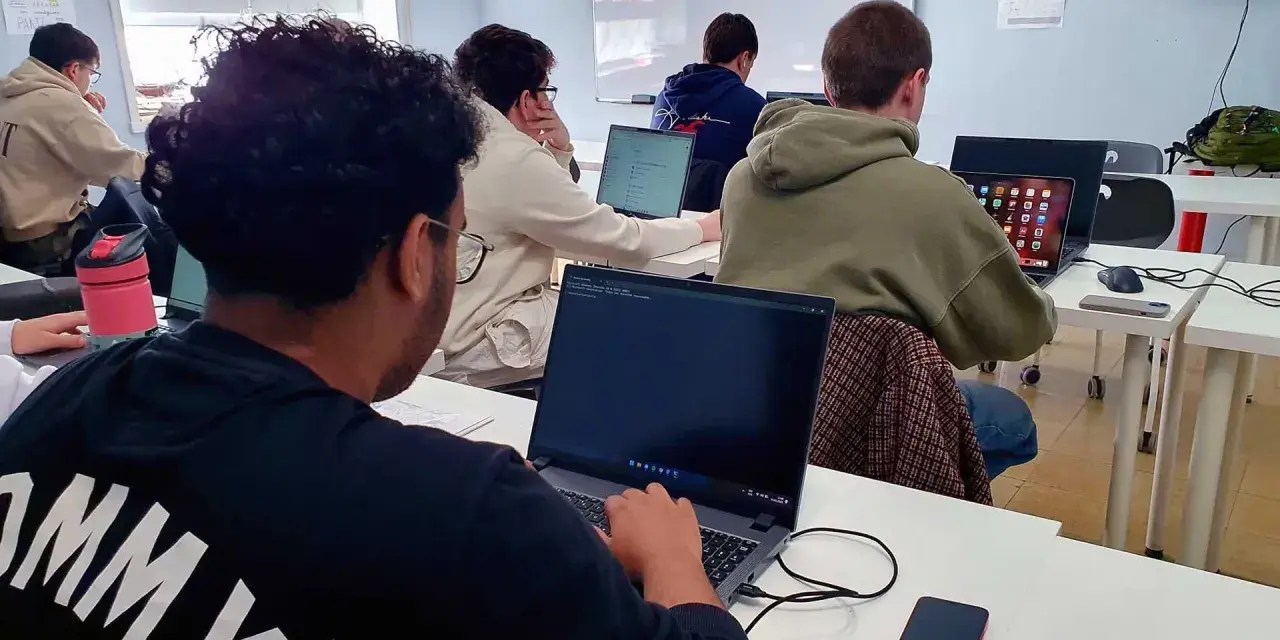 Estudiantes de **grado medio informática** concentrados frente a sus ordenadores en un aula.