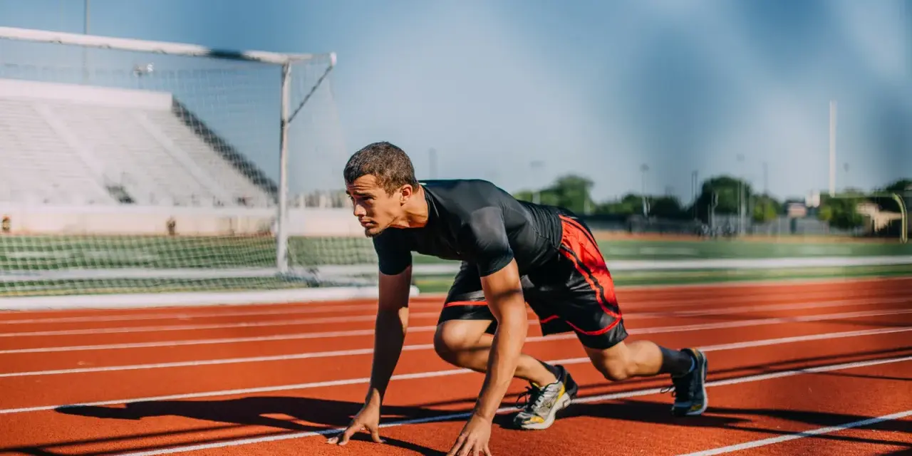 Atleta en posición de salida en pista de atletismo. ¿Cuánto cobra un profesor de educación física?