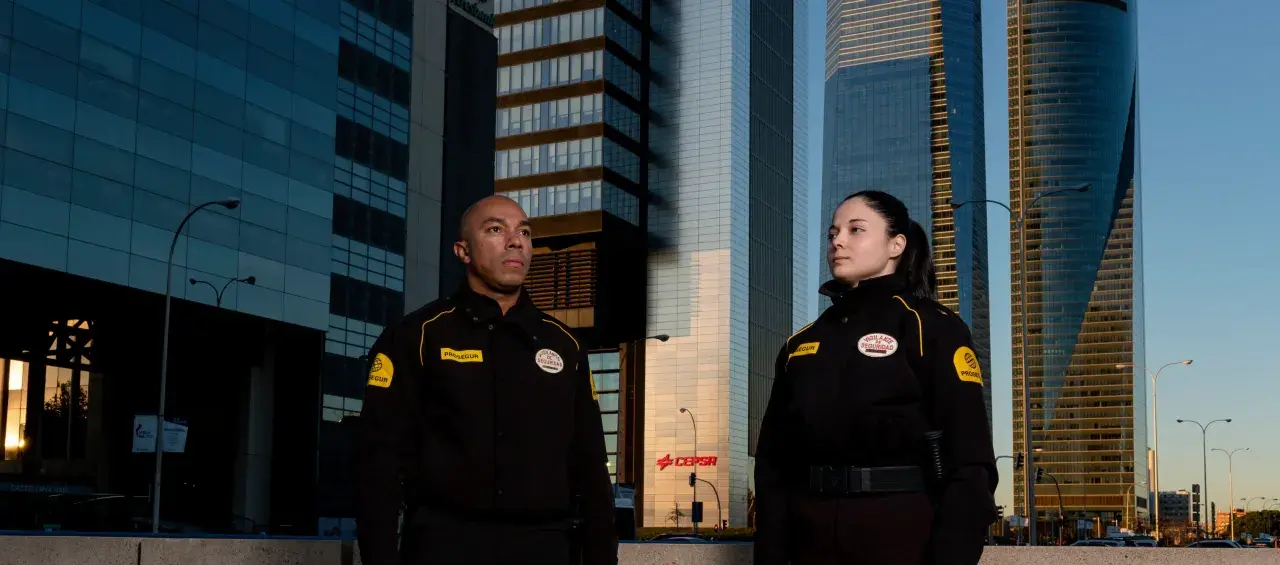 Dos vigilantes de seguridad posan frente a rascacielos. ¡Prepárate para tu curso vigilante de seguridad Asturias!