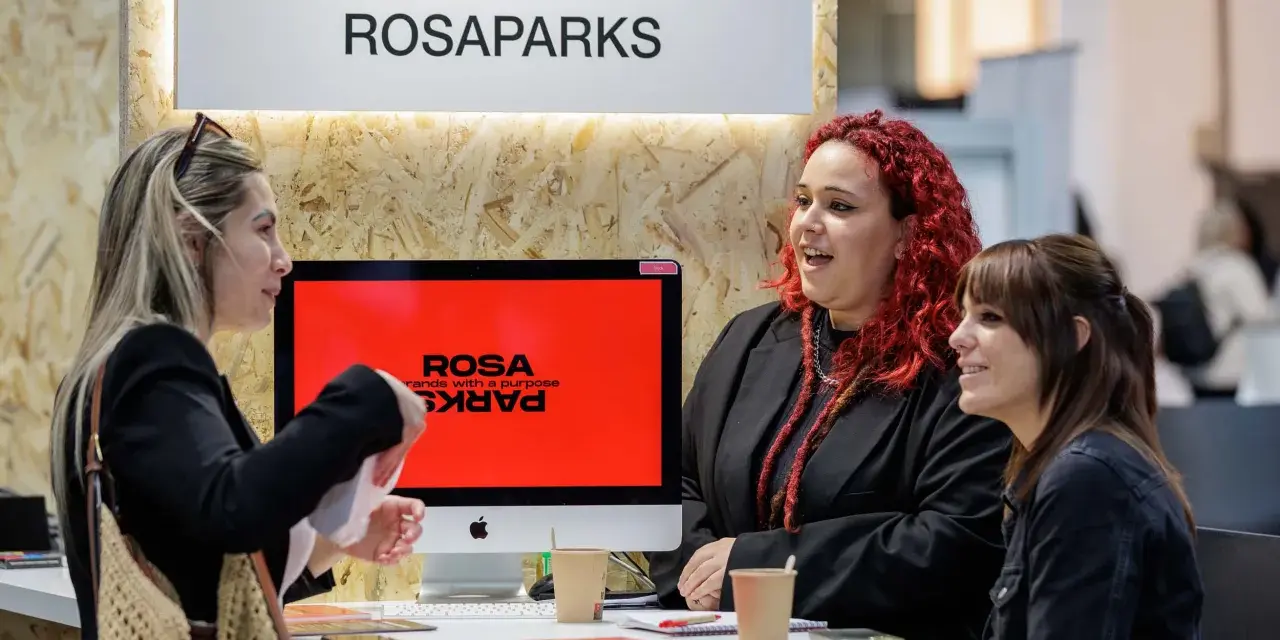 Tres mujeres conversan en un stand de ROSAPARKS, un evento de marketing en Barcelona.