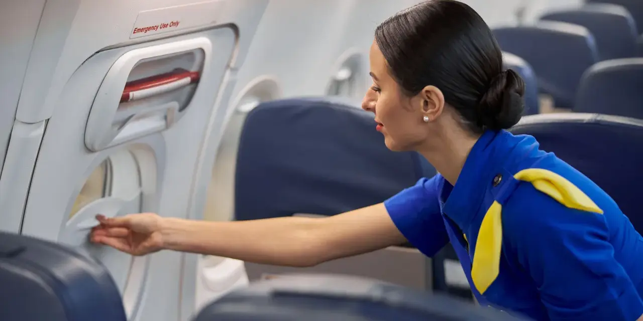 Una azafata de vuelo revisa un compartimento en el avión.