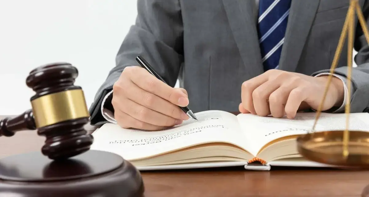 Un juez con toga y corbata escribe en un libro. A su lado, un mazo y la balanza de la justicia. ¿Cuánto cobra un juez en España?