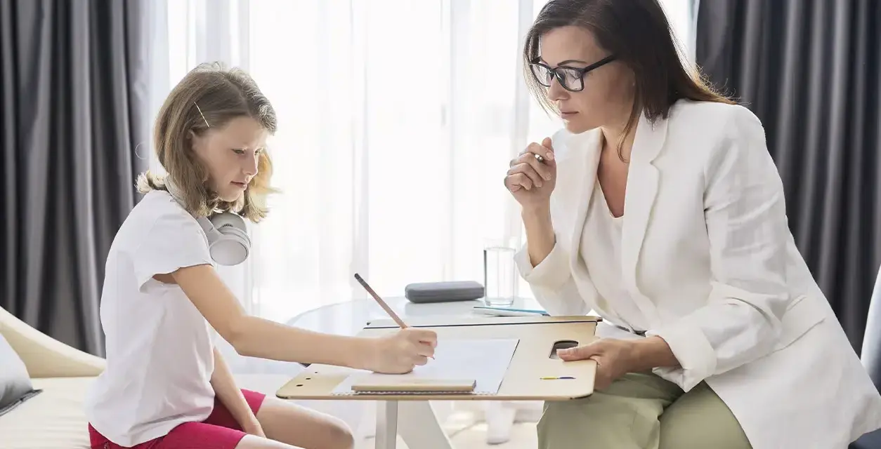 Psicóloga atenta a una niña que dibuja. La sesión es parte de la terapia infantil, y la pregunta de cuánto cobra un psicólogo en España es clave para acceder a estos servicios.