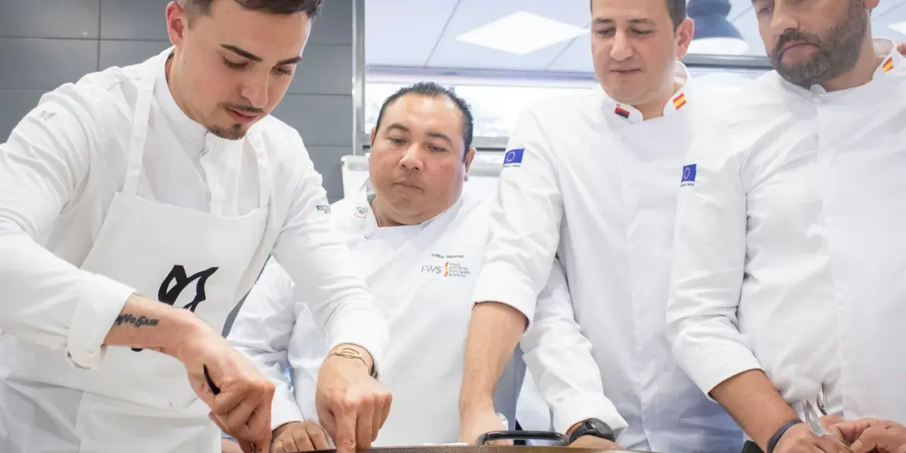 Cuatro chefs observan atentamente una paella. Se debate la diferencia entre chef y cocinero mientras preparan el plato.