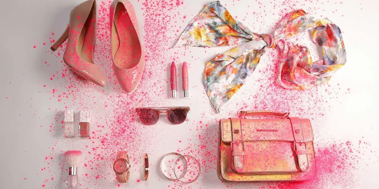 Zapatos, bolso, pañuelo, labiales, gafas de sol y accesorios de moda salpicados de polvo rosa.