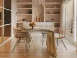 Comedor moderno con mesa de cristal y sillas de ratán. Estanterías empotradas y un toque de diseño de interiores cálido.