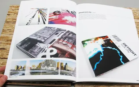 Un portfolio de diseño gráfico muestra una revista abierta con imágenes de arquitectura y arte abstracto, y un folleto de "Detroit rock city".