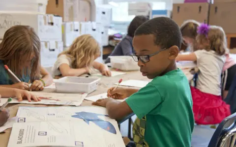 Niños concentrados en una actividad artística, guiados por un técnico superior en educación infantil.