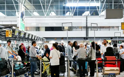 Gente haciendo fila para trabajar en el aeropuerto, con equipaje y mostradores de facturación.