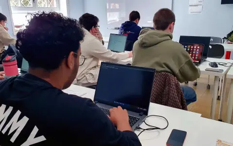 Estudiantes de **grado medio informática** concentrados frente a sus ordenadores en un aula.