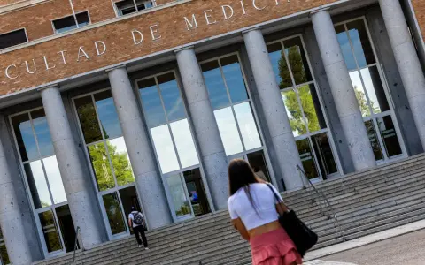 Fachada de la Facultad de Medicina, con estudiantes subiendo escaleras. Un futuro médico se dirige a una de las universidades privadas de medicina.