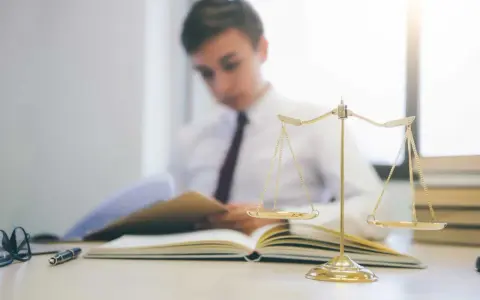 Estudiante de derecho concentrado en sus estudios, con una balanza de la justicia y libros. Averigua cuanto dura la carrera de derecho.