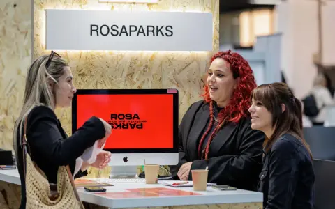 Tres mujeres conversan en un stand de ROSAPARKS, un evento de marketing en Barcelona.