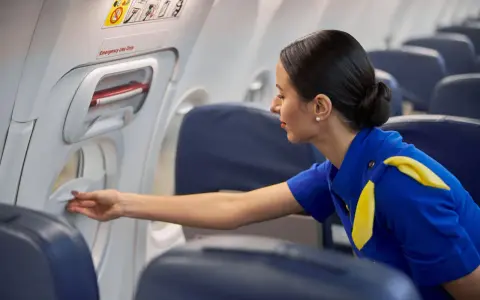 Una azafata de vuelo revisa un compartimento en el avión.