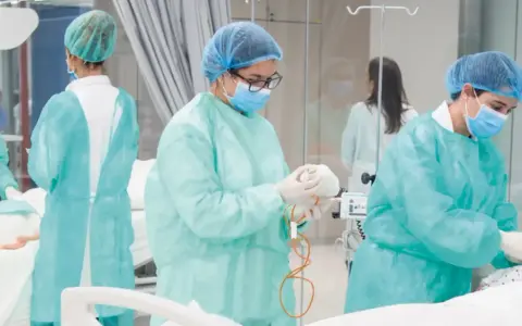 Estudiantes de enfermería en universidades privadas practican en un entorno clínico, vestidas con batas y mascarillas.