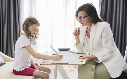 Psicóloga atenta a una niña que dibuja. La sesión es parte de la terapia infantil, y la pregunta de cuánto cobra un psicólogo en España es clave para acceder a estos servicios.