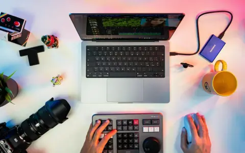 Un escritorio con un portátil mostrando un editor de video, un teclado de control, cámara, disco duro y taza. Ideal para los mejores editores de video para PC.