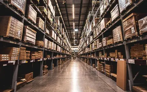 Pasillo de almacén con estanterías altas repletas de cajas, esencial para la valoración de existencias.