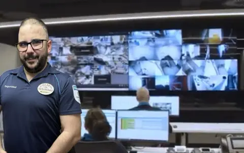 Vigilante de seguridad con certificado de discapacidad, sonriendo ante cámaras de vigilancia.