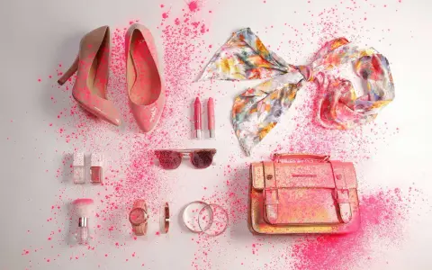 Zapatos, bolso, pañuelo, labiales, gafas de sol y accesorios de moda salpicados de polvo rosa.