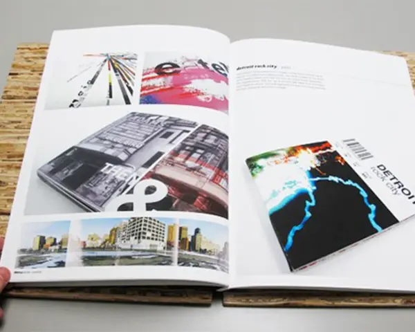 Un portfolio de diseño gráfico muestra una revista abierta con imágenes de arquitectura y arte abstracto, y un folleto de "Detroit rock city".