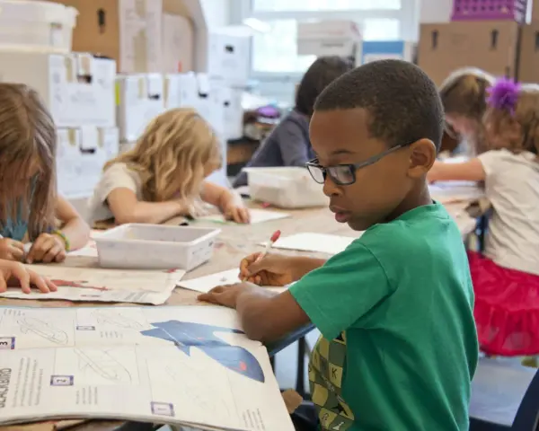 Niños concentrados en una actividad artística, guiados por un técnico superior en educación infantil.