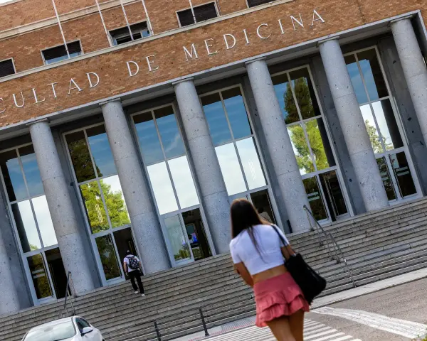 Fachada de la Facultad de Medicina, con estudiantes subiendo escaleras. Un futuro médico se dirige a una de las universidades privadas de medicina.