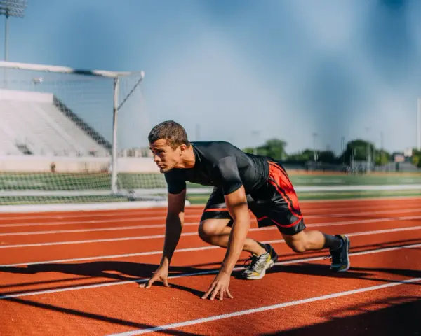 Atleta en posición de salida en pista de atletismo. ¿Cuánto cobra un profesor de educación física?