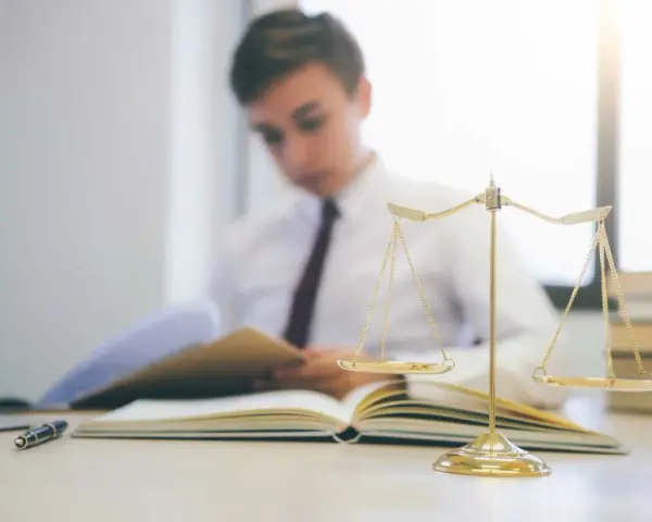 Estudiante de derecho concentrado en sus estudios, con una balanza de la justicia y libros. Averigua cuanto dura la carrera de derecho.