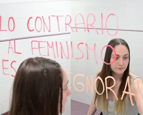 Joven reflexiona ante el espejo, escribiendo "Lo contrario al feminismo es ignorancia". Un mensaje para quienes estudian técnico superior en promoción de igualdad de género online.